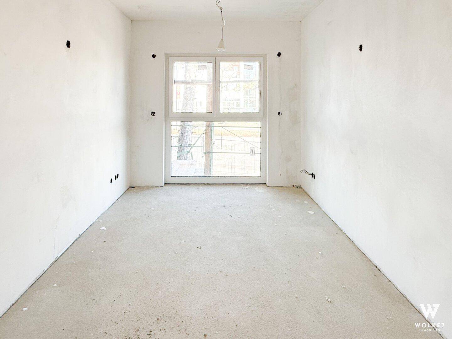 Leerer Raum im Rohbau mit großem Fenster, ideal für Schlafzimmer oder Büro.