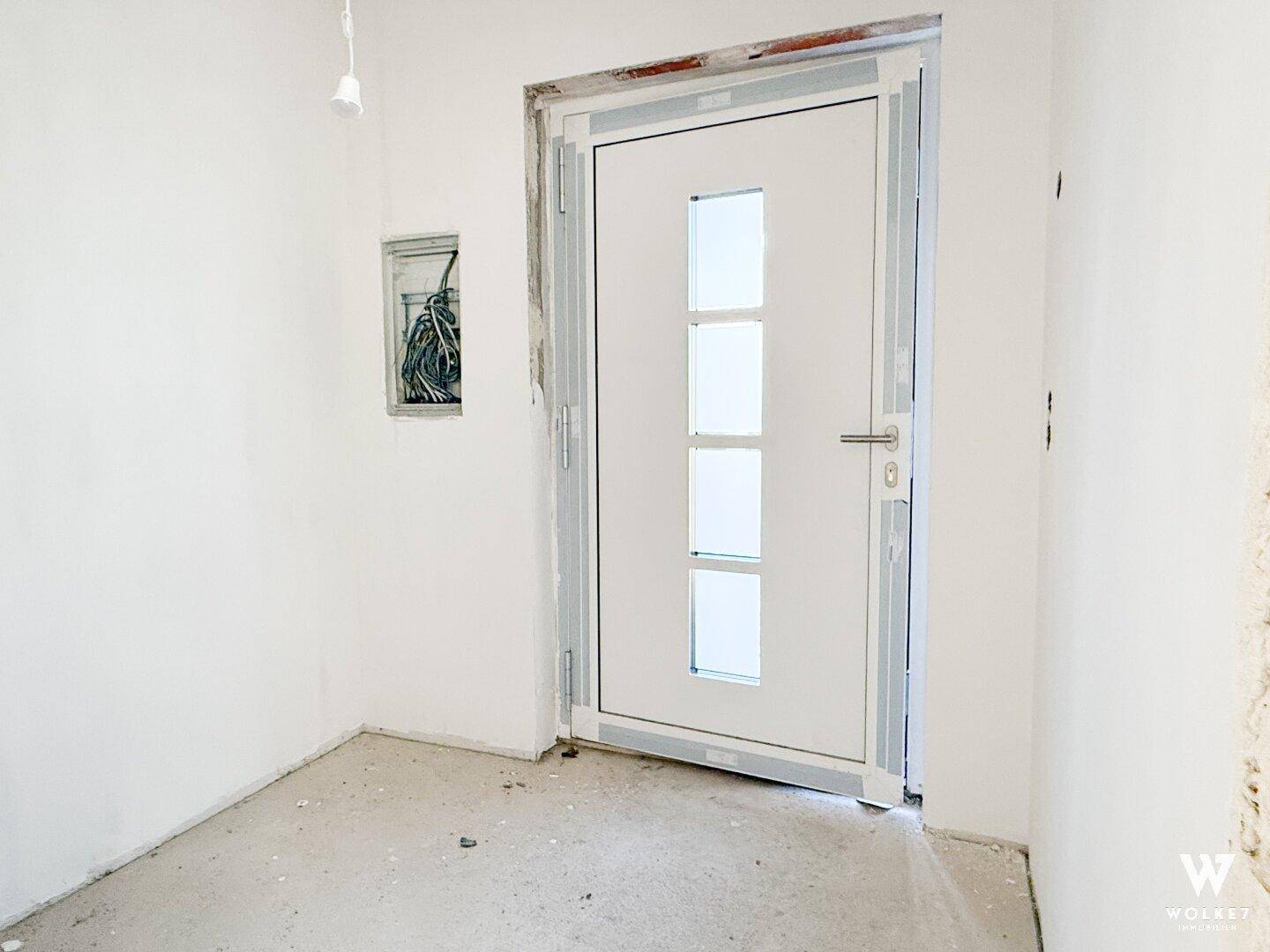 Moderne Eingangstür mit Glaseinsätzen in einem noch unfertigen Flurbereich.