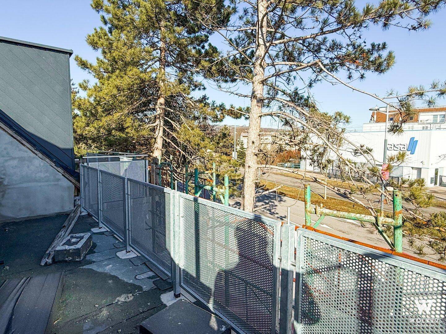 Blick von der oberen Etage auf die Umgebung mit Bäumen und Gebäuden.