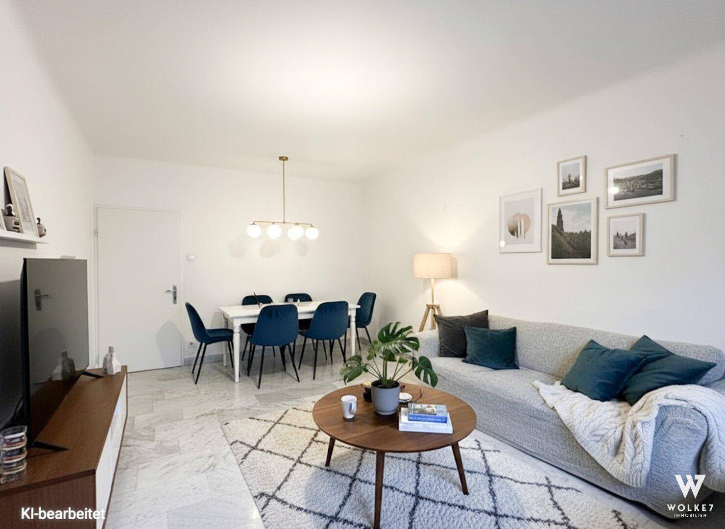 Gemütlicher Wohnbereich mit hellem Sofa und Essbereich mit blauen Stühlen, alles auf Marmorboden.