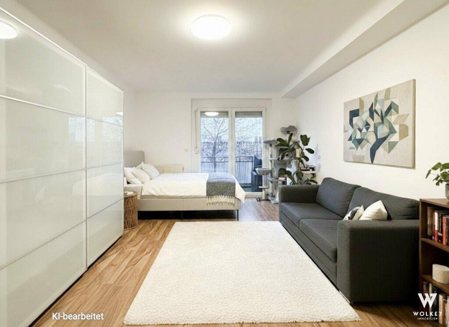 Schlafzimmer mit großem Bett, Sofa und Zugang zu einem Balkon, ausgestattet mit Holzfußboden.