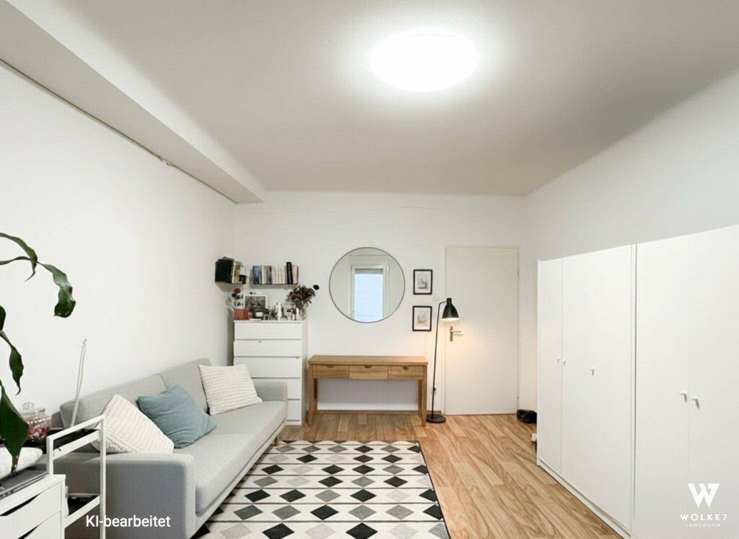 Helles Zimmer mit Sofa, Schreibtisch und weißen Schränken, ideal als Schlaf- oder Arbeitsbereich.