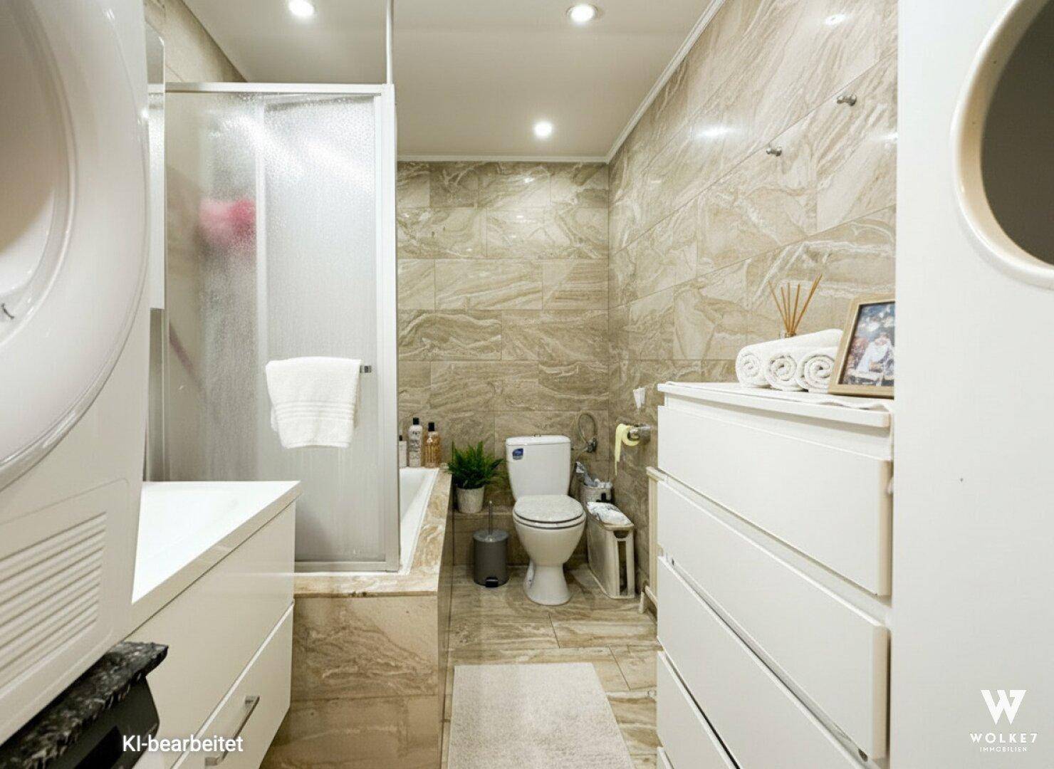 Modernes Badezimmer mit Dusche, WC und Waschmaschine, ausgestattet mit beigen Fliesen.