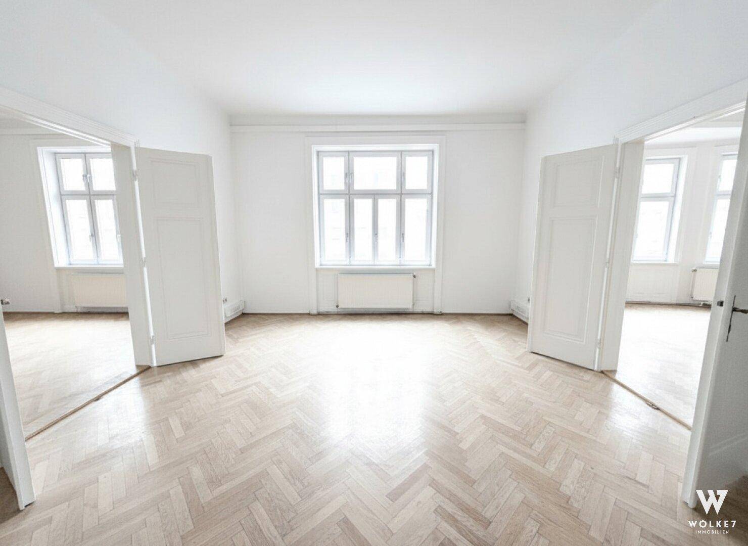 Leerer, heller Raum mit klassischem Fischgrätparkett, weißen Wänden und einem großen Fenster, das viel Licht spendet.