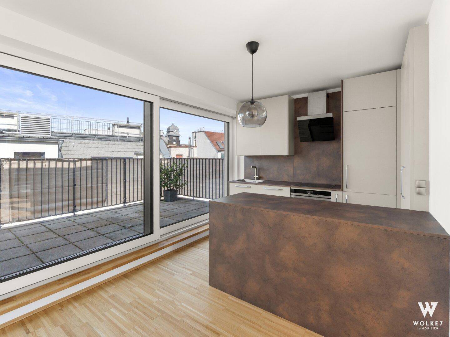 Moderne Küche mit Kücheninsel, integrierten Geräten und direktem Zugang zu einer geräumigen Terrasse.