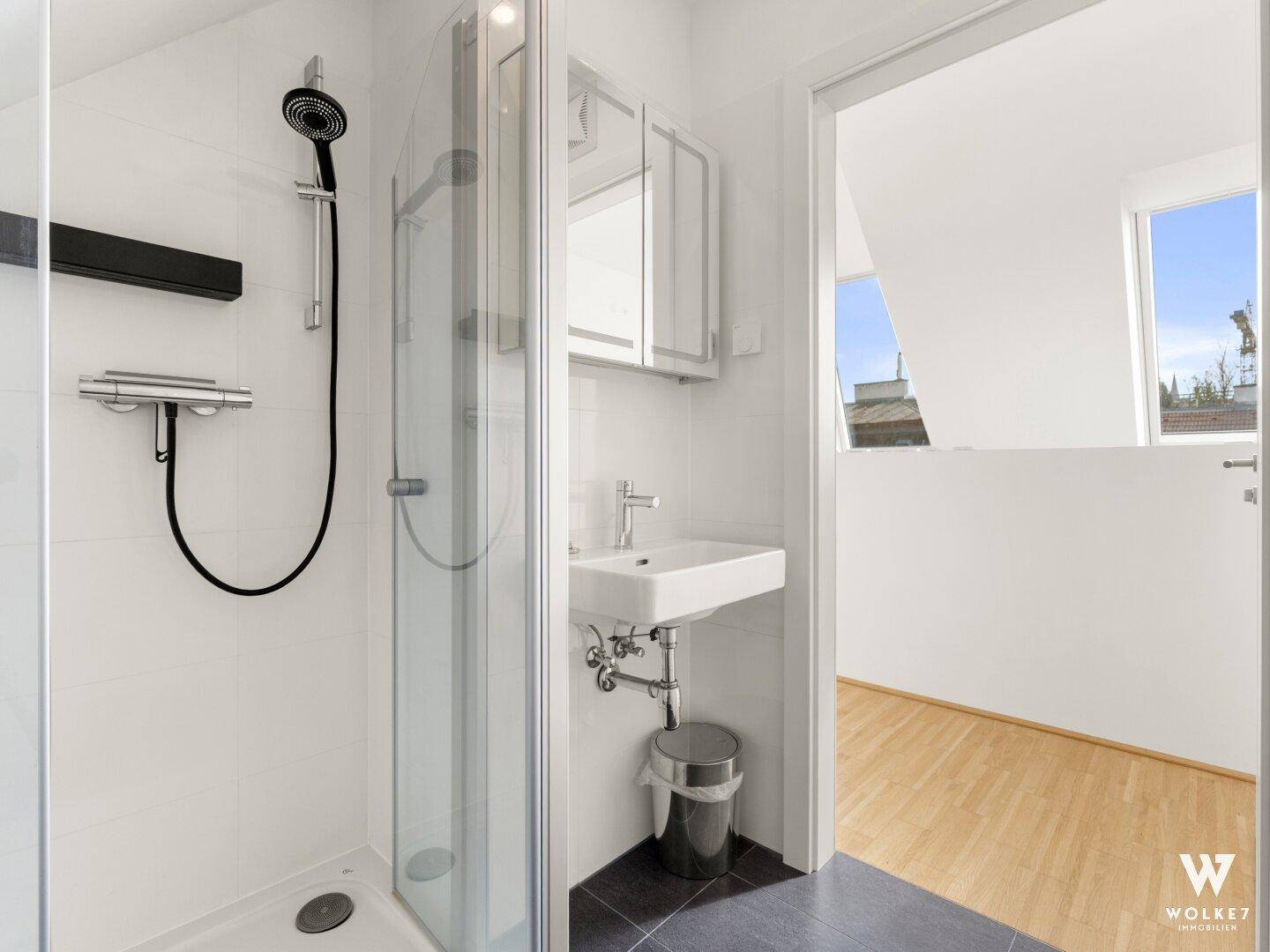 Modernes Badezimmer mit Duschkabine, Waschbecken und Spiegelschrank, hell gefliest.