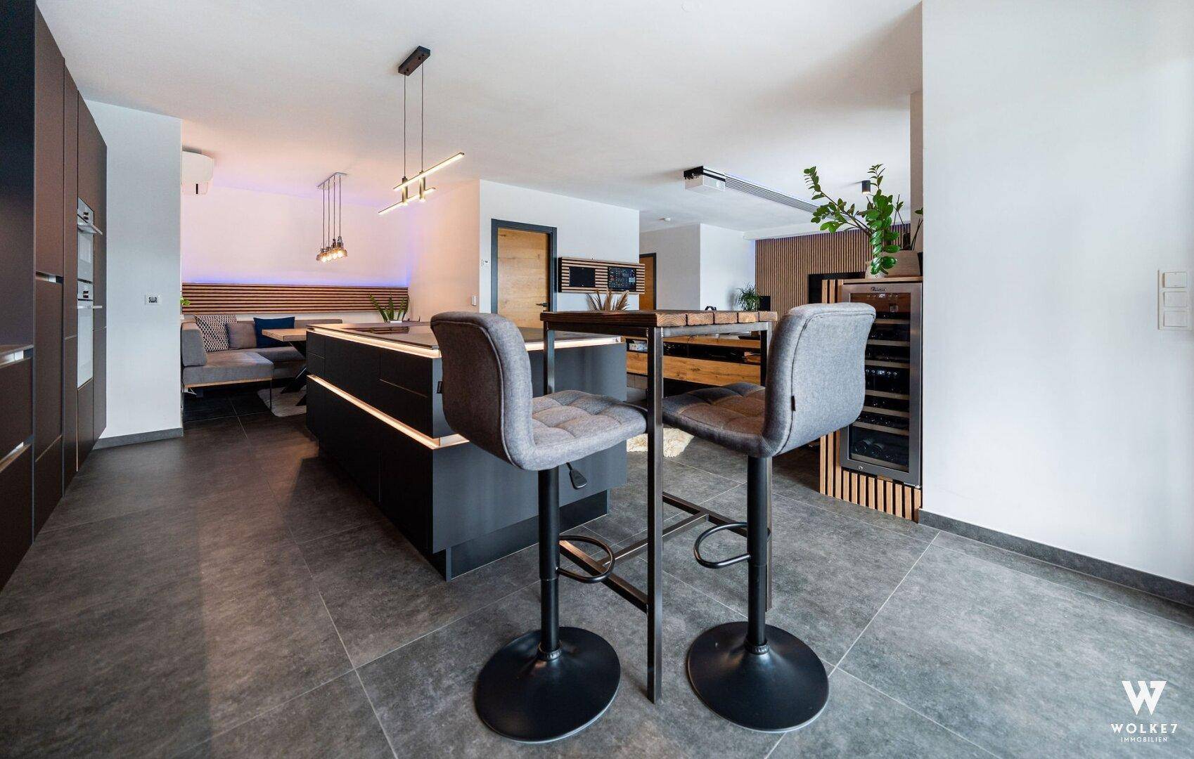 Offene, moderne Küche mit dunklen Schränken, Kücheninsel und integrierter Frühstücksbar.