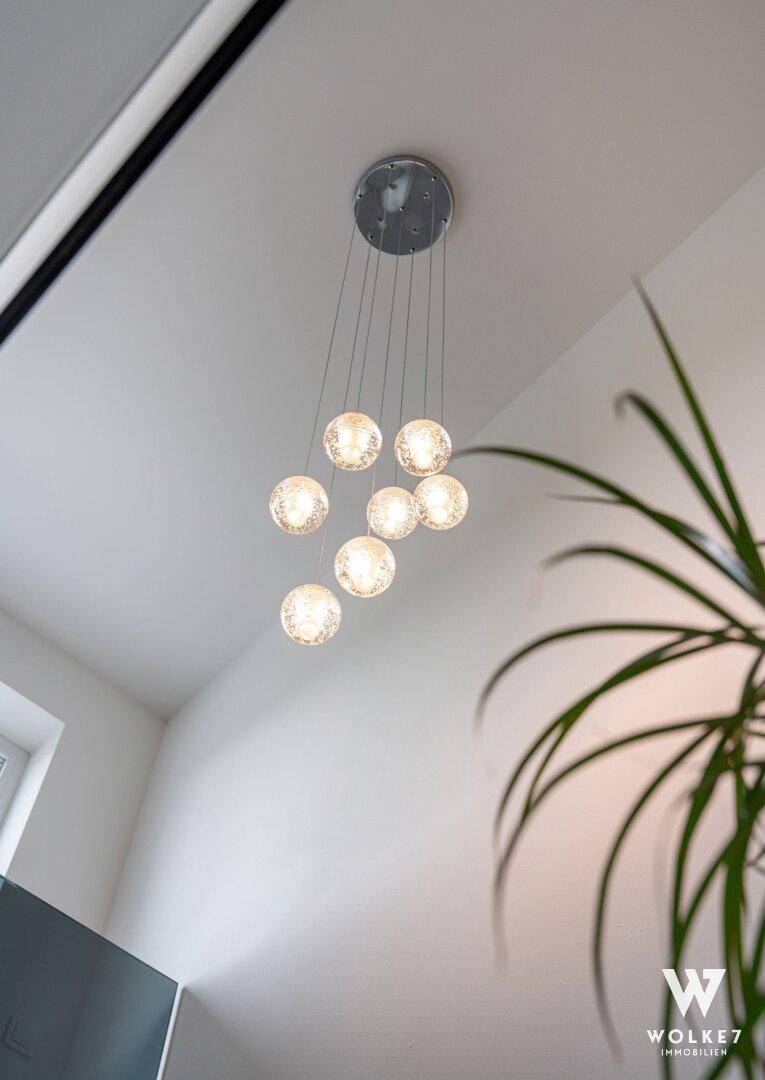 Moderne Deckenleuchte mit mehreren kugelförmigen Glaselementen in einem hellen Raum.