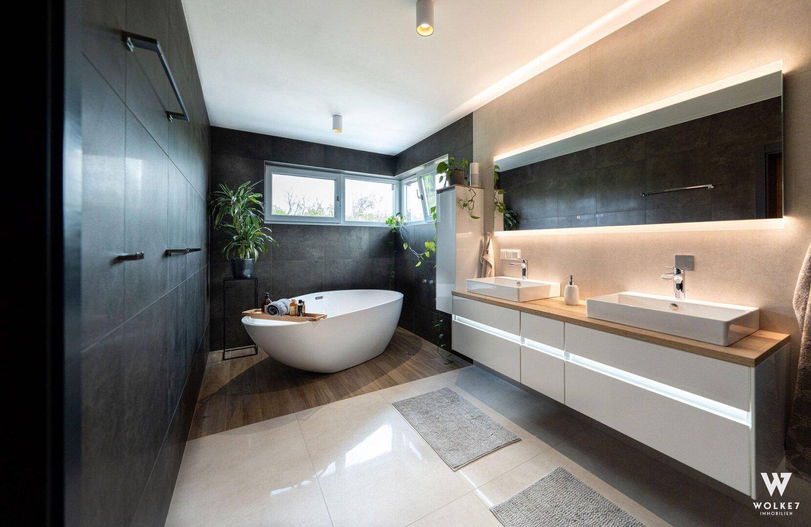 Geräumiges Luxusbadezimmer mit freistehender Badewanne, Doppelwaschbecken und großen Fenstern.