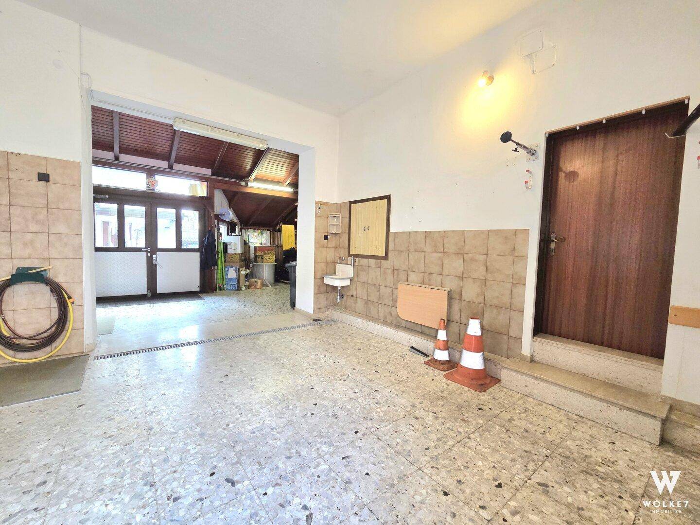 Geräumige Garage mit gefliestem Boden und viel Platz für Fahrzeuge und Lagerung.