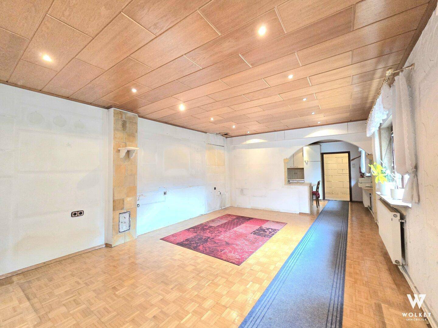 Geräumiges Wohnzimmer mit Holzdecke und Parkettboden, bereit für eine individuelle Gestaltung.