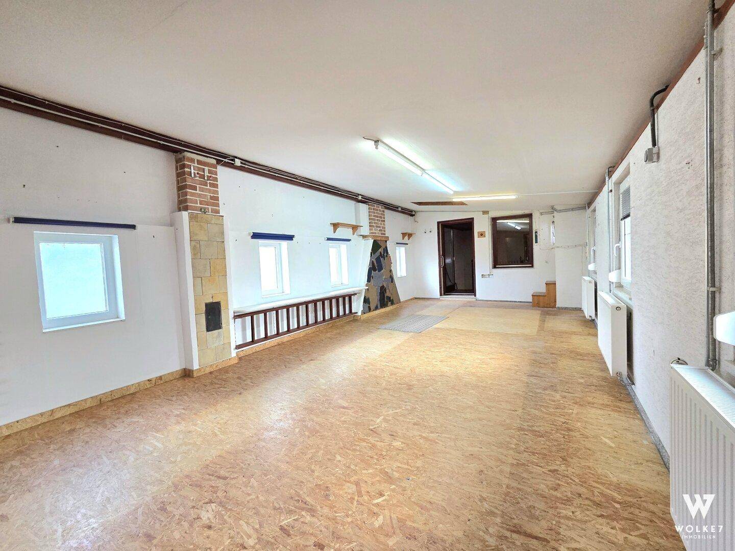 Geräumiger Kellerraum mit OSB-Plattenboden und sichtbaren Holzbalken, ideal als Lagerfläche.