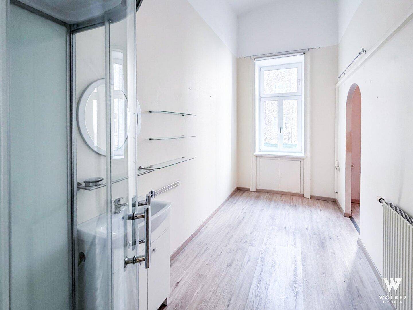 Badezimmer mit Duschkabine, Waschbecken und Fenster, das für natürliche Belüftung sorgt.