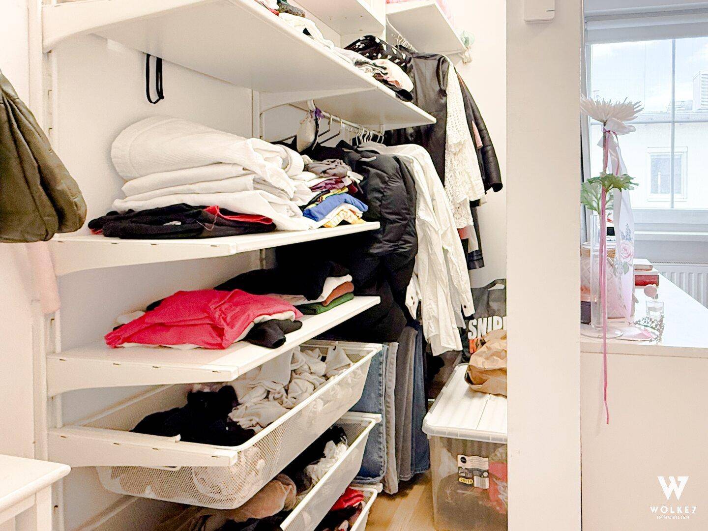 Begehbarer Kleiderschrank mit offenen Regalen und viel Stauraum für Kleidung.