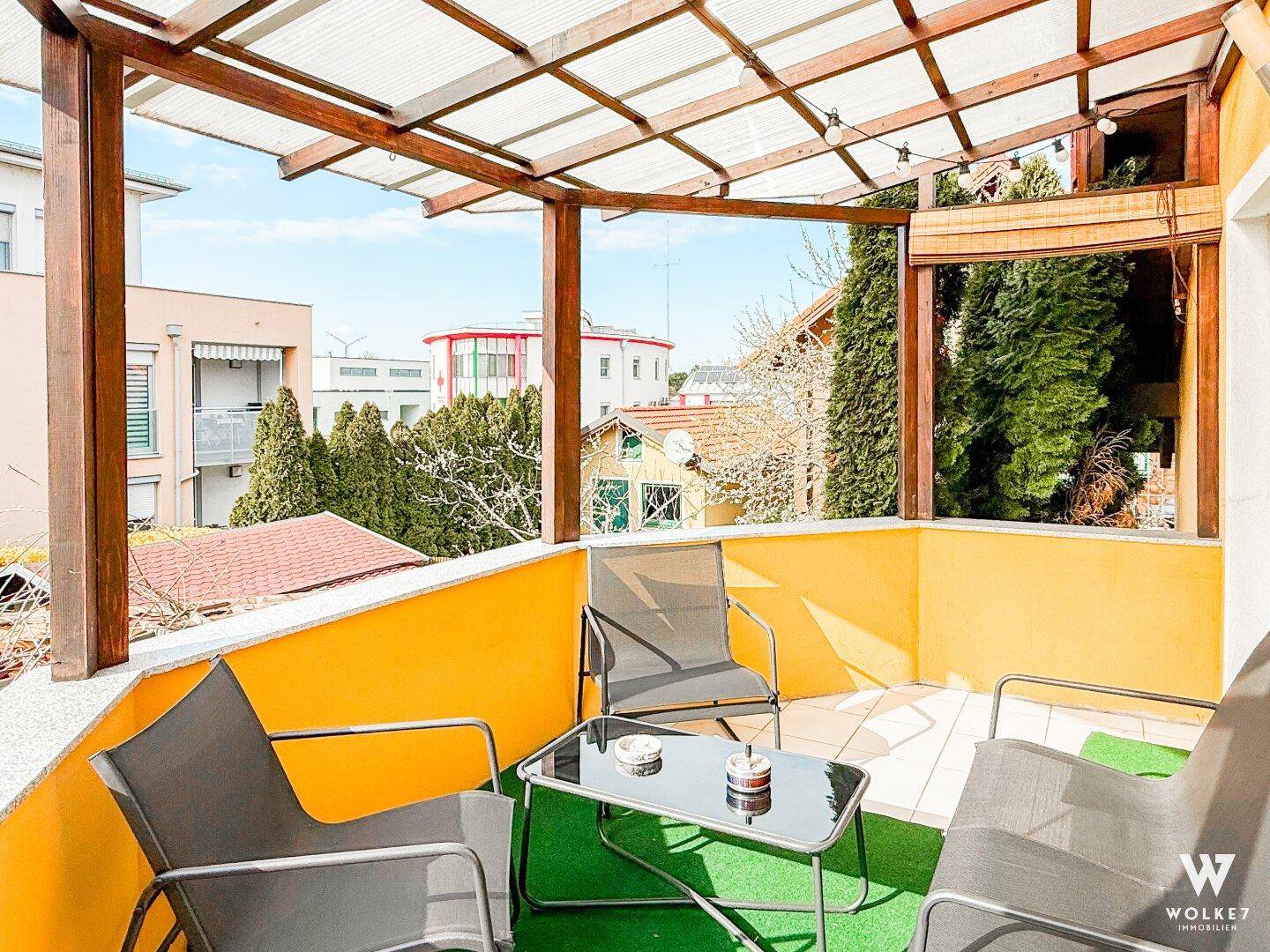 Überdachter Balkon mit Sitzgelegenheiten und Blick auf die Umgebung.