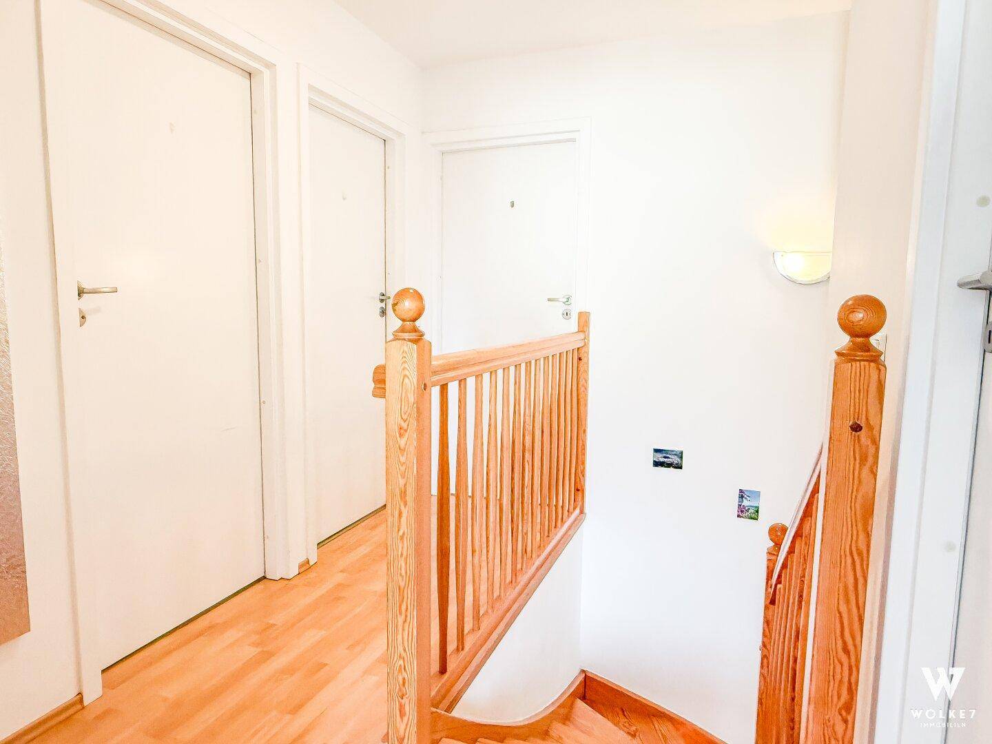 Heller Flur mit Holztreppe und Zugang zu weiteren Räumen im Obergeschoss.