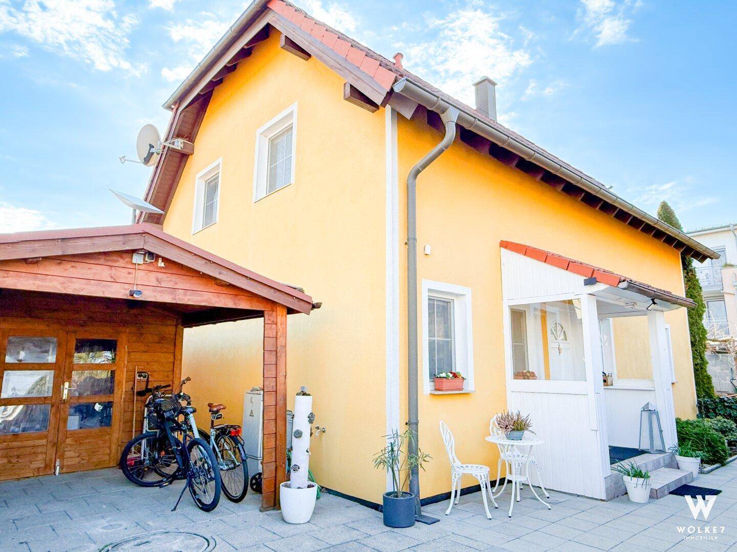 Gelbes Haus mit Carport, Fahrrädern und einem einladenden überdachten Eingangsbereich.