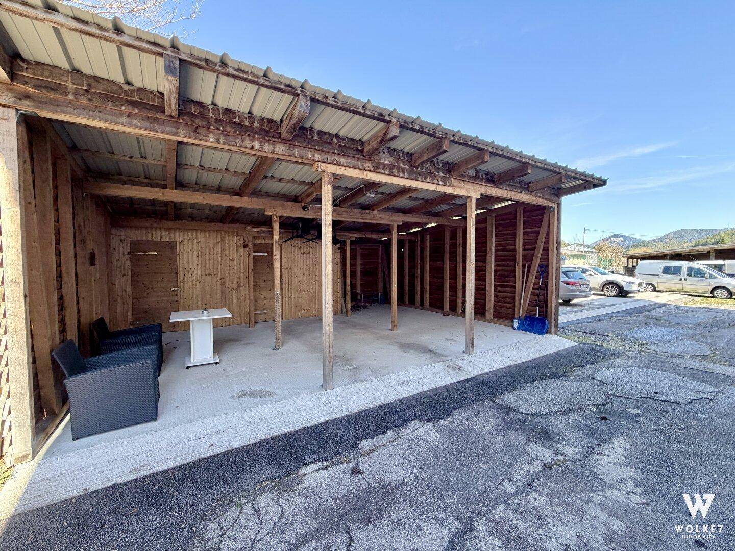 Überdachter Carport-Bereich mit Holzkonstruktion und Sitzgelegenheiten im Freien.