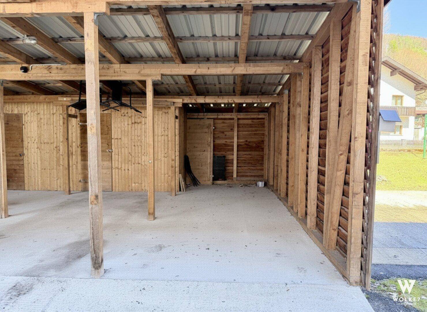 Geräumiger Carport mit Holzkonstruktion, bietet Schutz für Fahrzeuge.