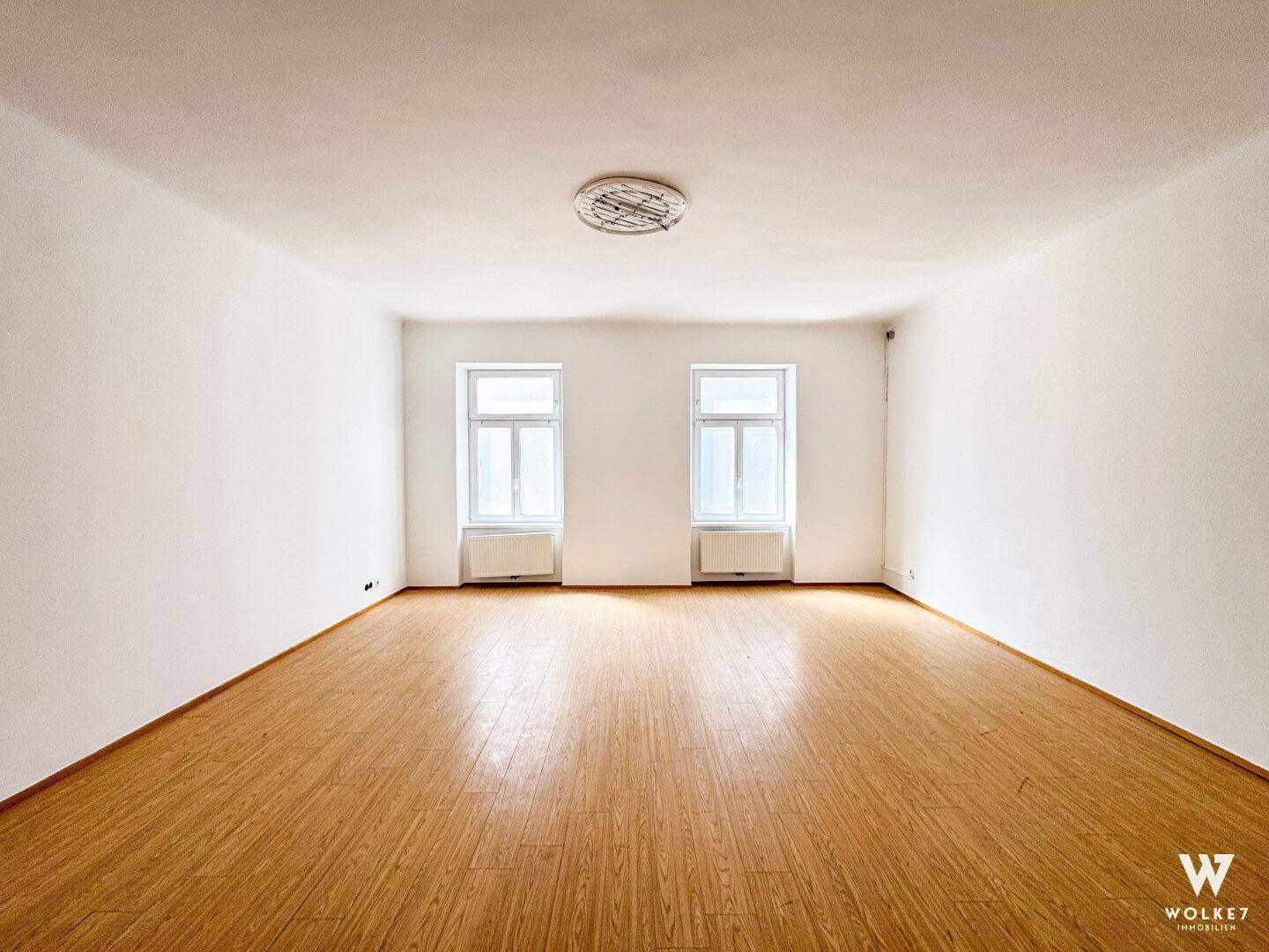 Heller, leerer Raum mit Laminatboden und zwei Fenstern, ideal für Büro oder Wohnzwecke.