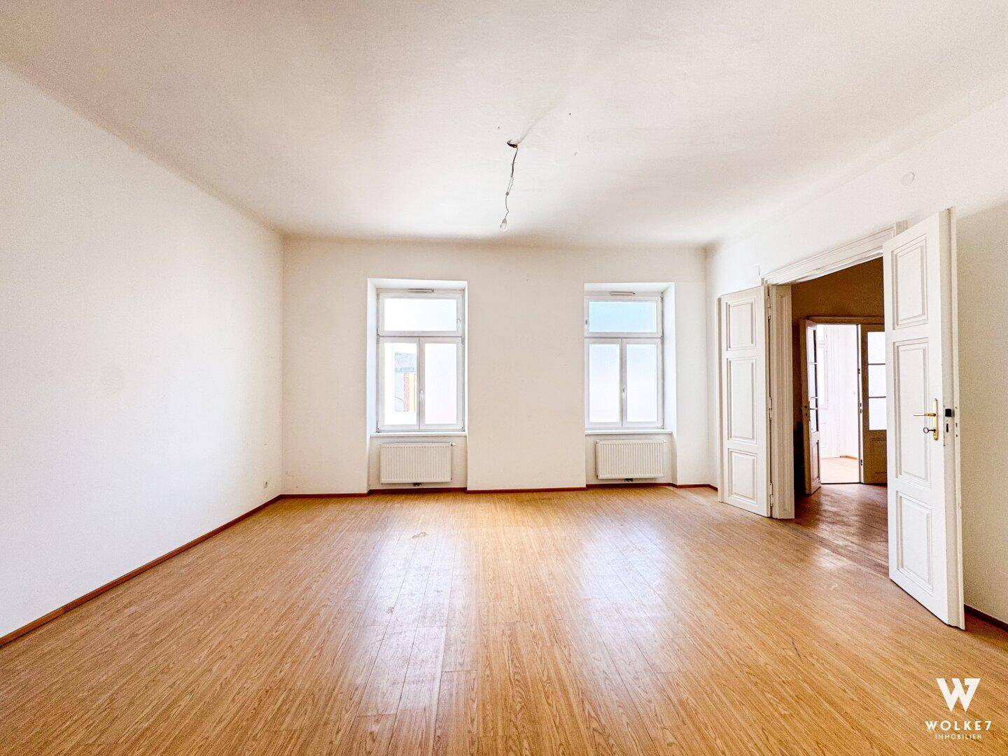 Großes, leeres Büro mit Laminatboden und hohen Fenstern, bietet vielseitige Nutzungsmöglichkeiten.