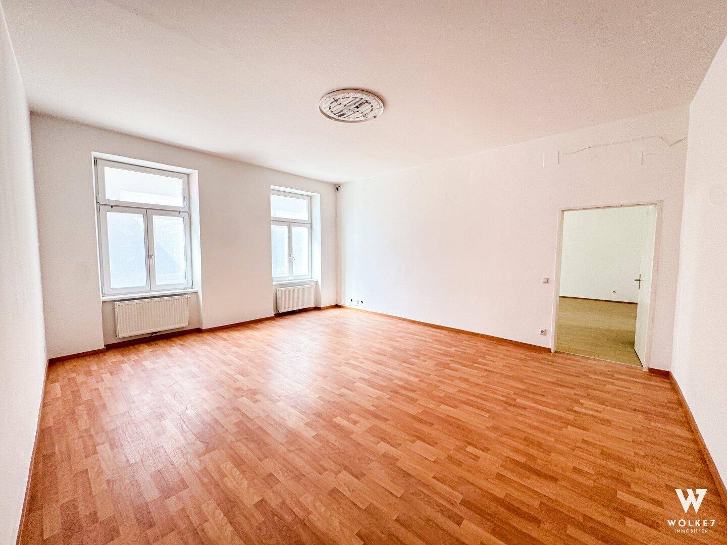 Geräumiges, leeres Büro mit Laminatboden und weißen Wänden, bereit zur individuellen Gestaltung.