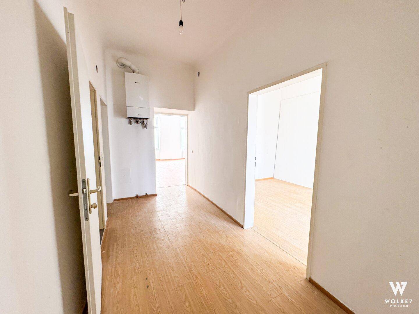 Langer Flur mit Laminatboden und weißen Wänden, führt zu verschiedenen Räumen der Immobilie.