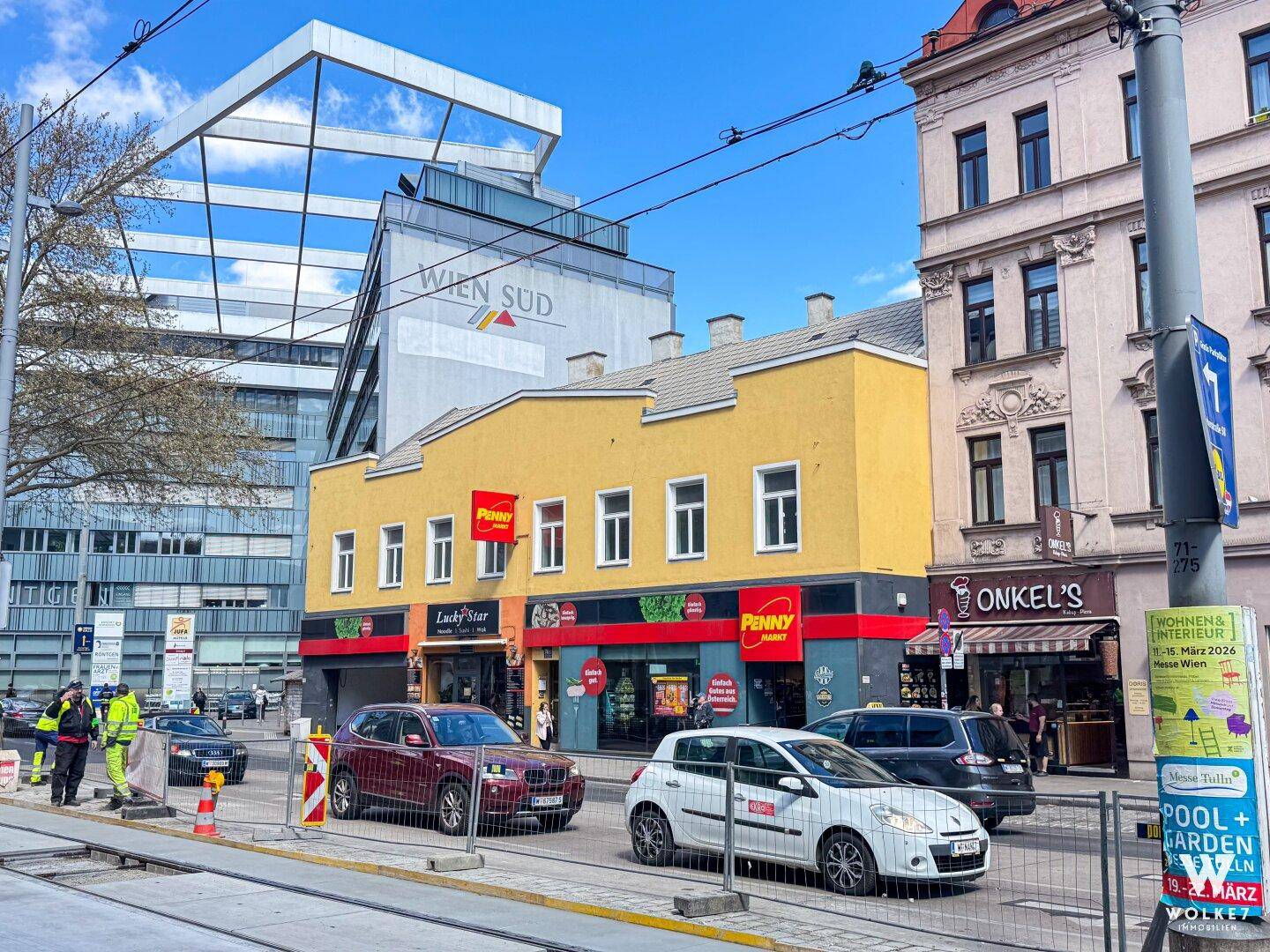 Lebhafte Stadtstraße mit Geschäften und Gebäuden unter blauem Himmel, zeigt städtisches Umfeld.