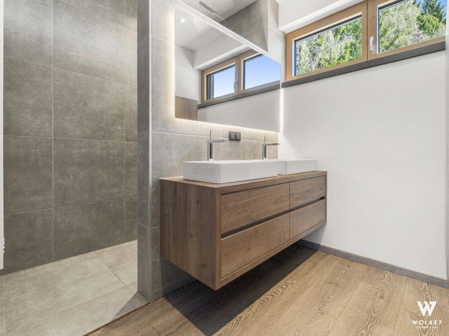 Modernes Badezimmer mit Doppelwaschbecken, großem Spiegel und einer geräumigen begehbaren Dusche.