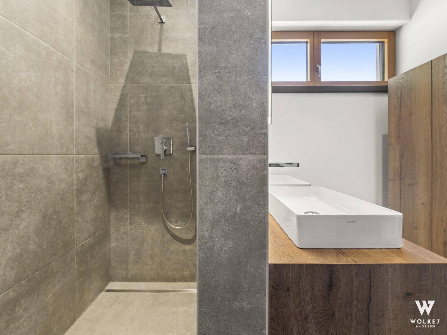 Detailansicht der modernen begehbaren Dusche und des Waschbeckens im stilvollen Badezimmer.
