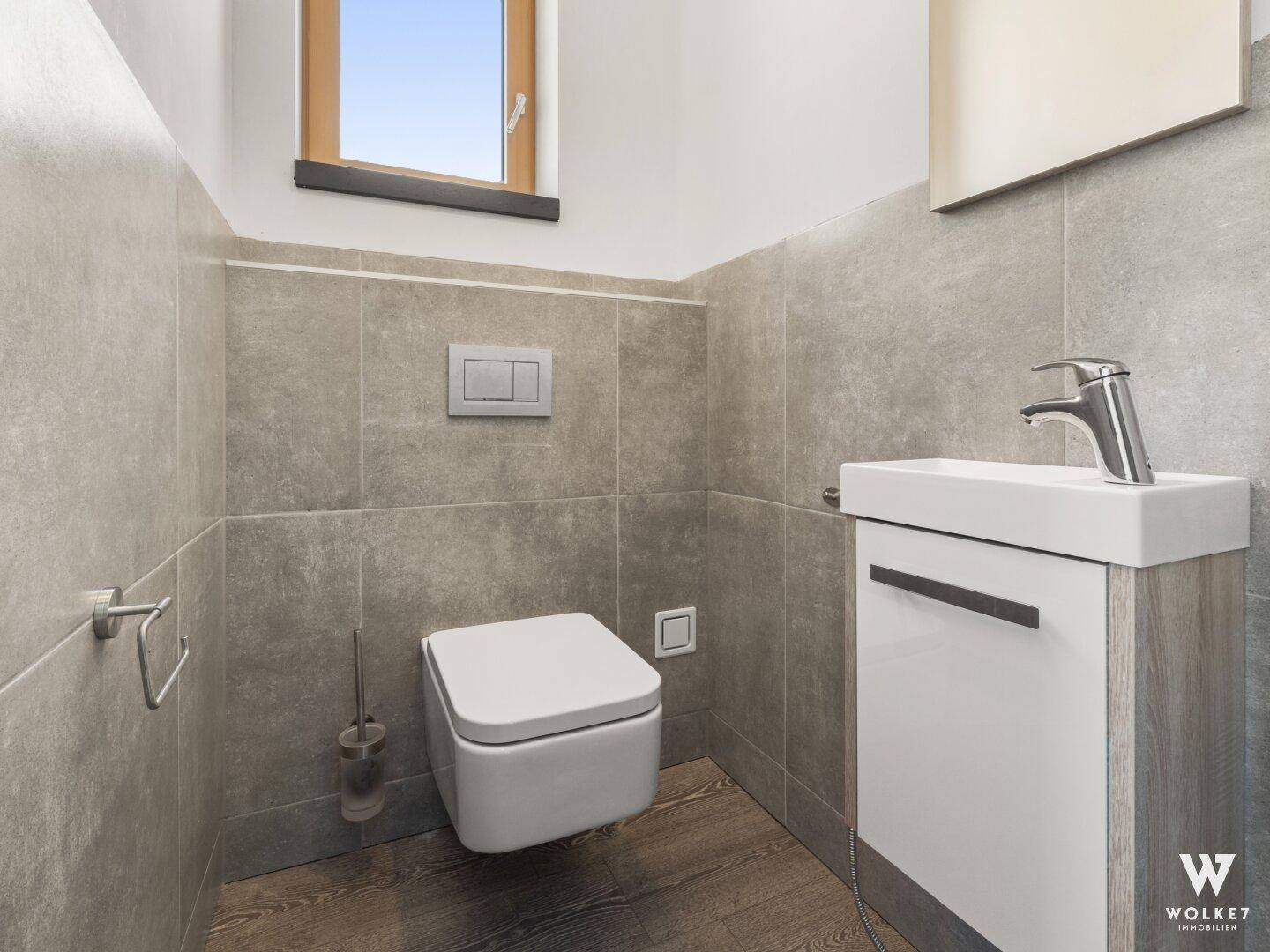 Modernes Gäste-WC mit wandhängender Toilette, kleinem Waschbecken und Fenster für Tageslicht.