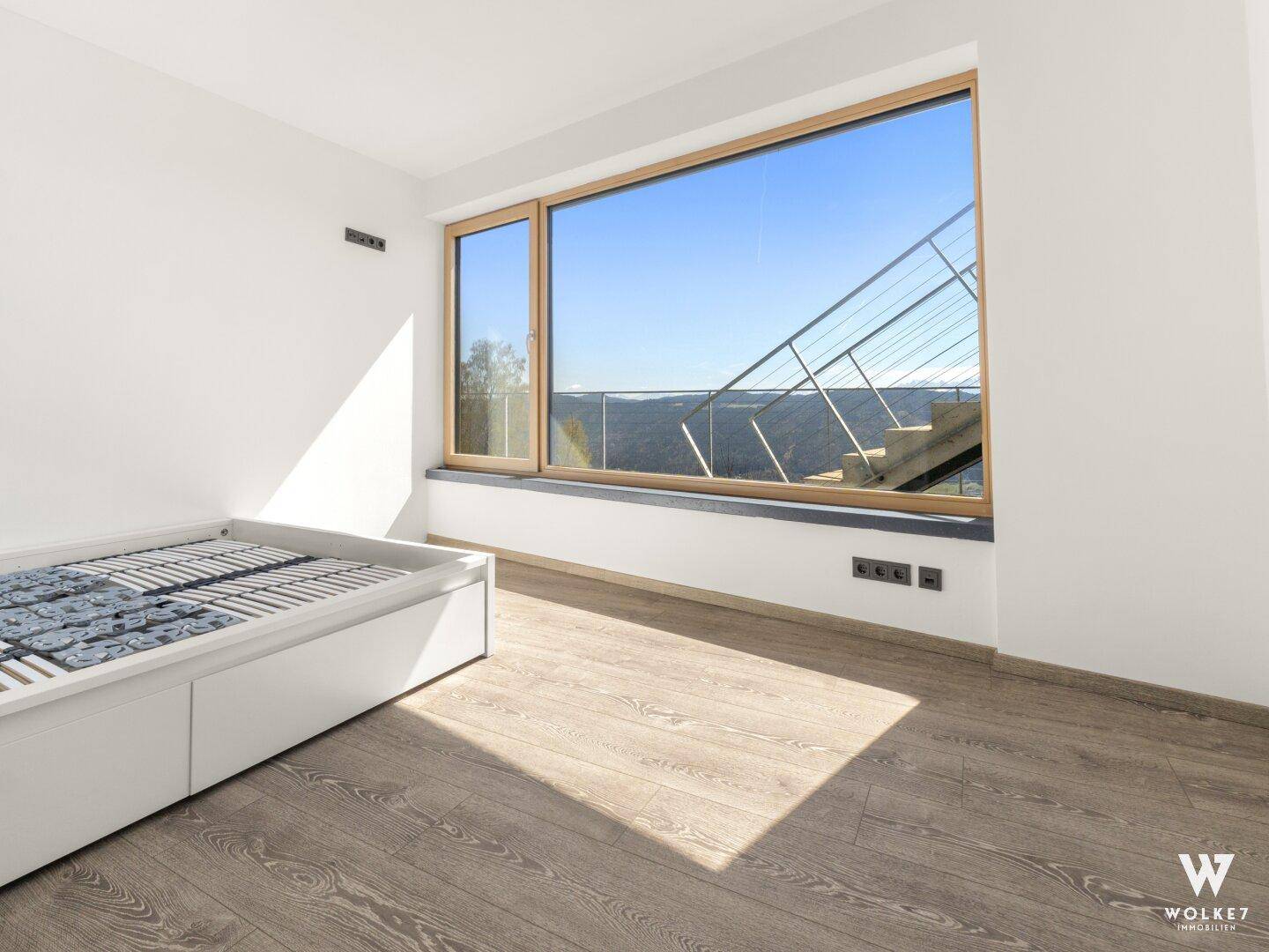 Unmöbliertes Schlafzimmer mit großem Fenster, das viel Tageslicht und einen weiten Blick bietet.