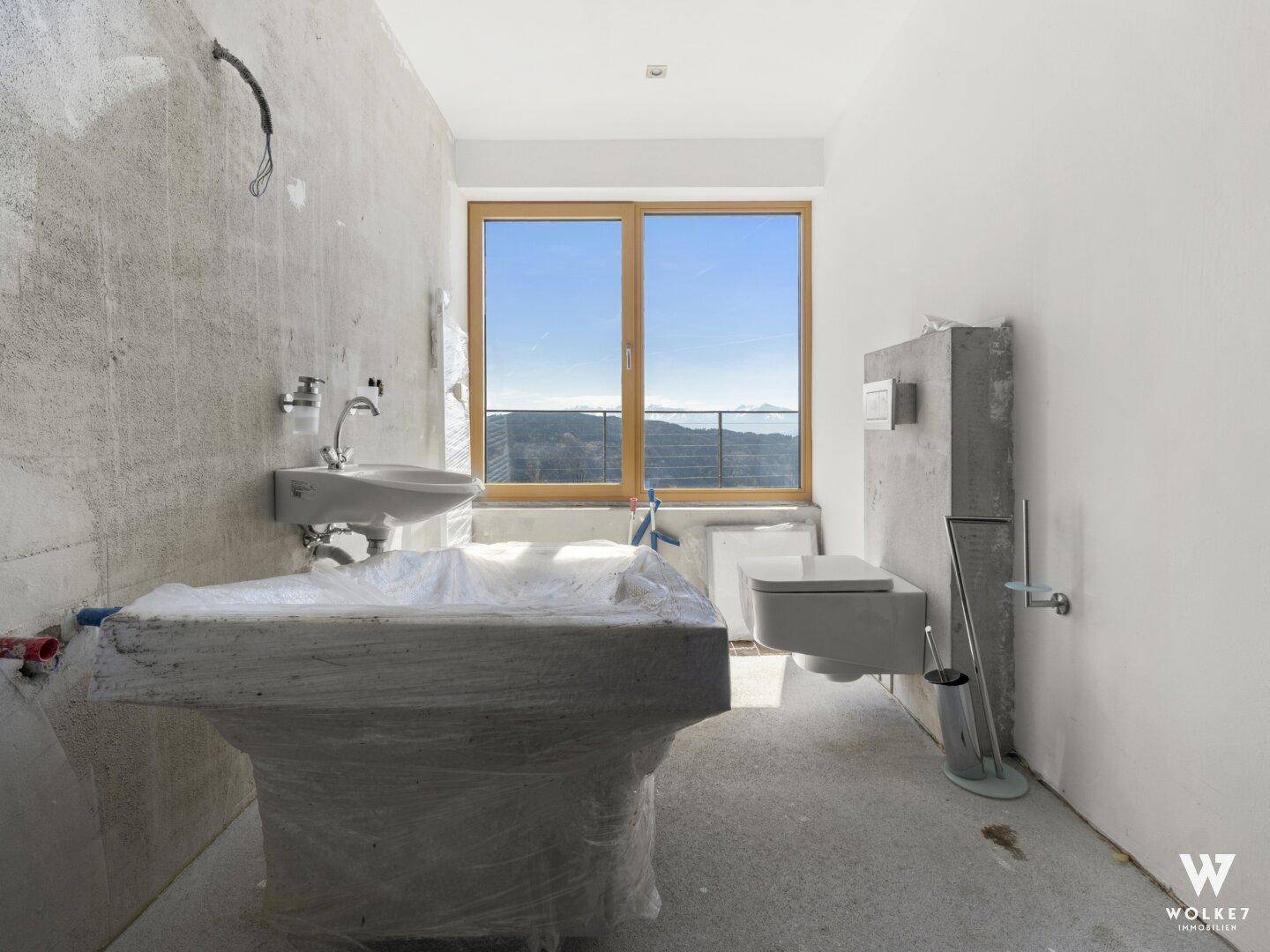 Badezimmer im Rohbauzustand mit sichtbaren Betonwänden, Toilette und Waschbecken, bereit für den Ausbau.