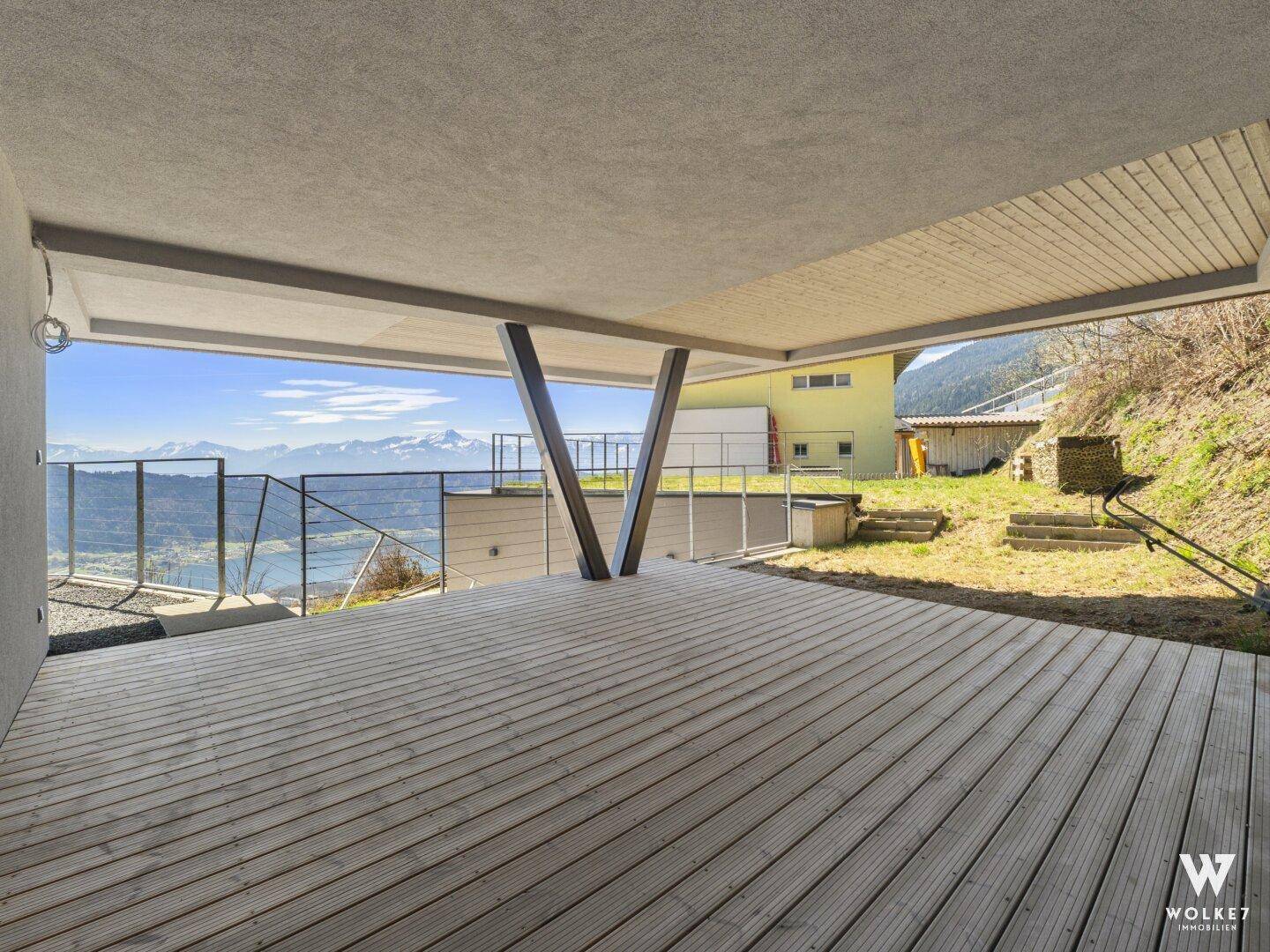 Überdachte Terrasse mit Holzfußboden und weitem Blick auf die umliegende Landschaft und die Berge.