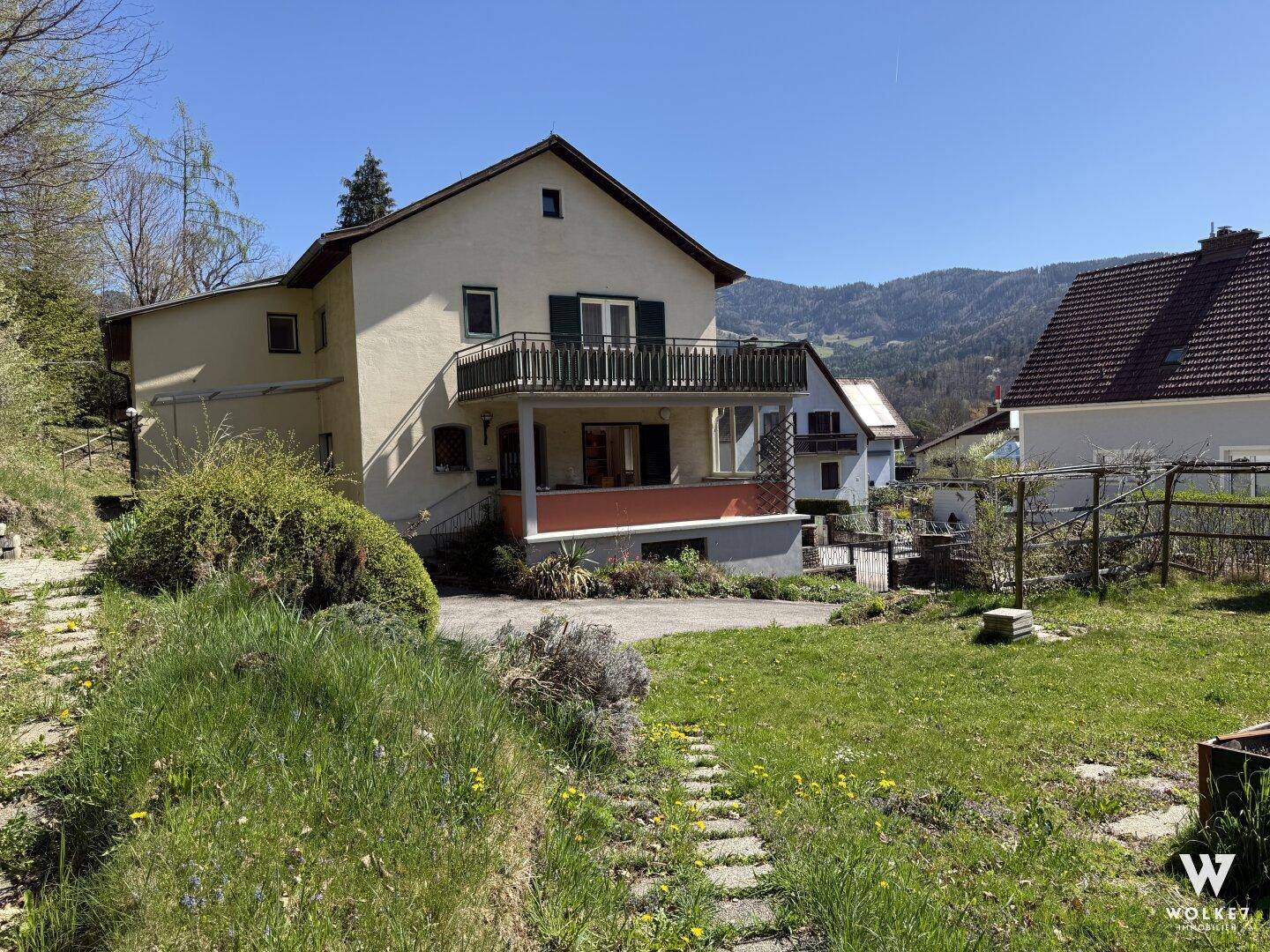 Großer Gartenbereich mit Rasenfläche und Blick auf das Haus und die Berge.
