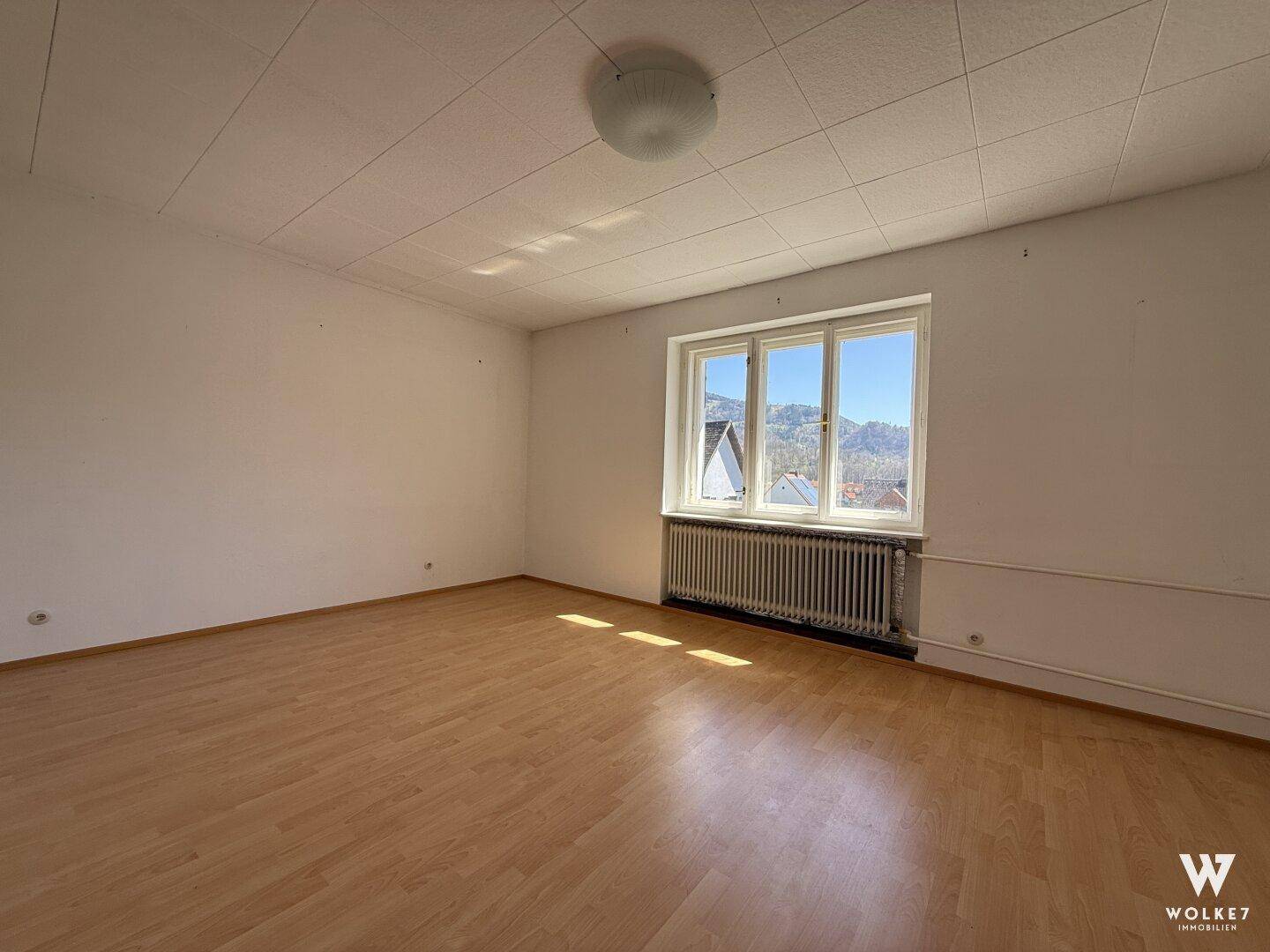 Helles Schlafzimmer mit Laminatboden und weitem Blick auf die umliegenden Berge.