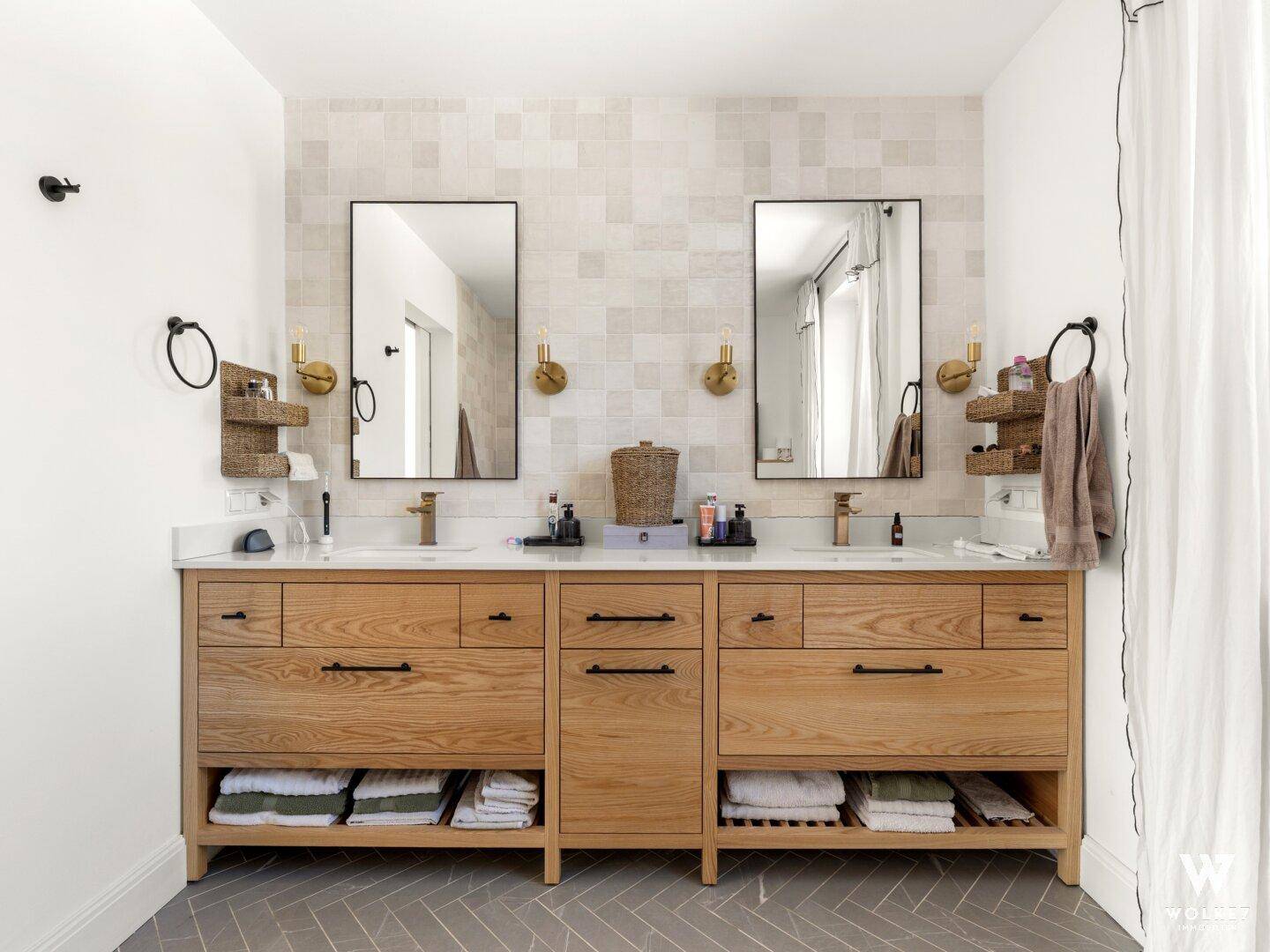 Elegantes Badezimmer mit Doppelwaschbecken, Holzunterschrank und großen Spiegeln.