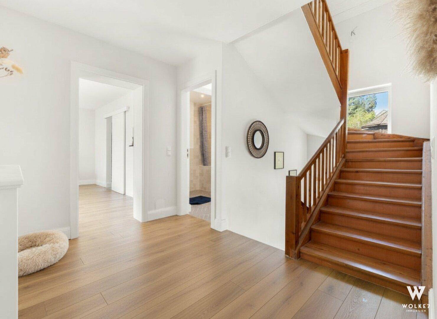 Treppenhaus mit Holztreppe und hellem Holzboden, das zu den oberen Etagen führt.