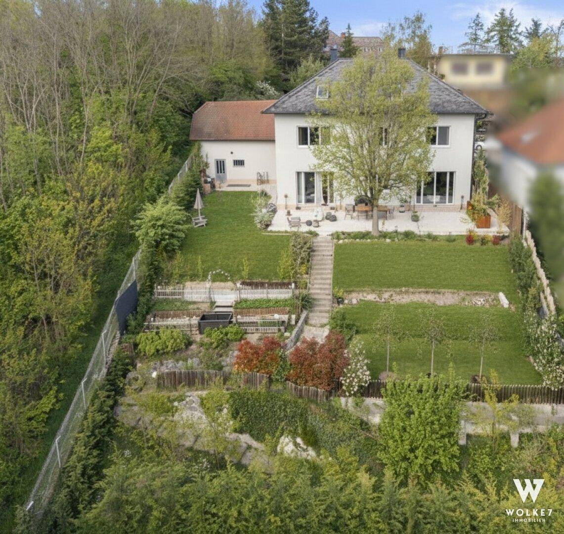 Luftaufnahme des Hauses mit großem, terrassiertem Garten und viel Grünfläche.