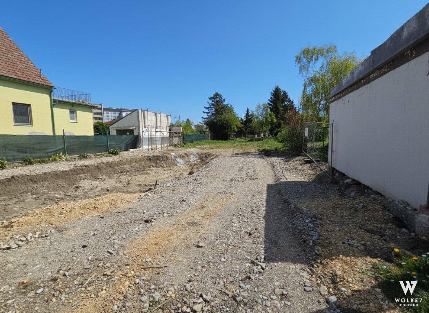 Unbebautes Grundstück mit Schotterweg und vorbereiteter Baufläche in ländlicher Umgebung.