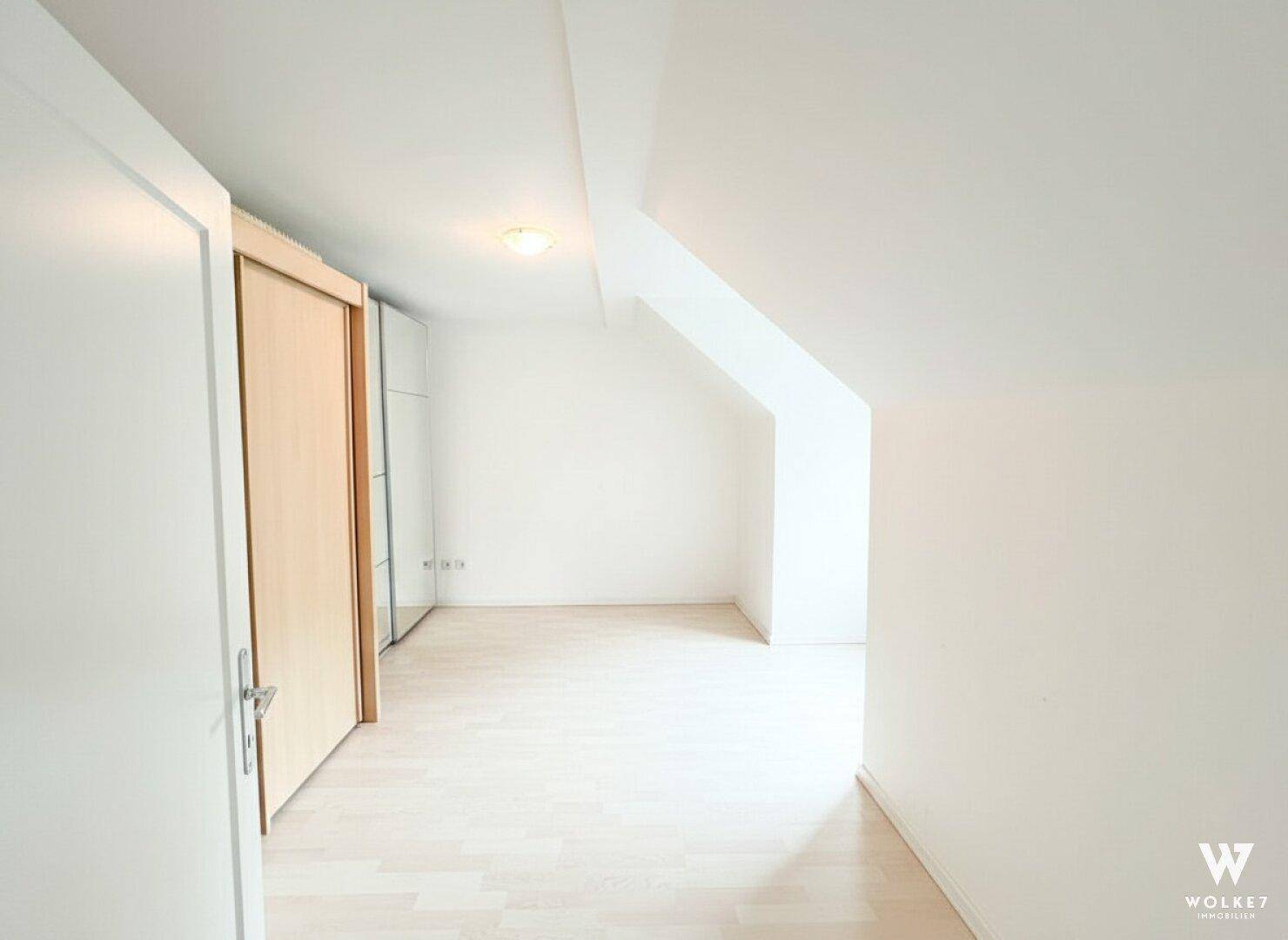 Leeres Schlafzimmer im Dachgeschoss mit hellem Holzboden und Dachschrägen.