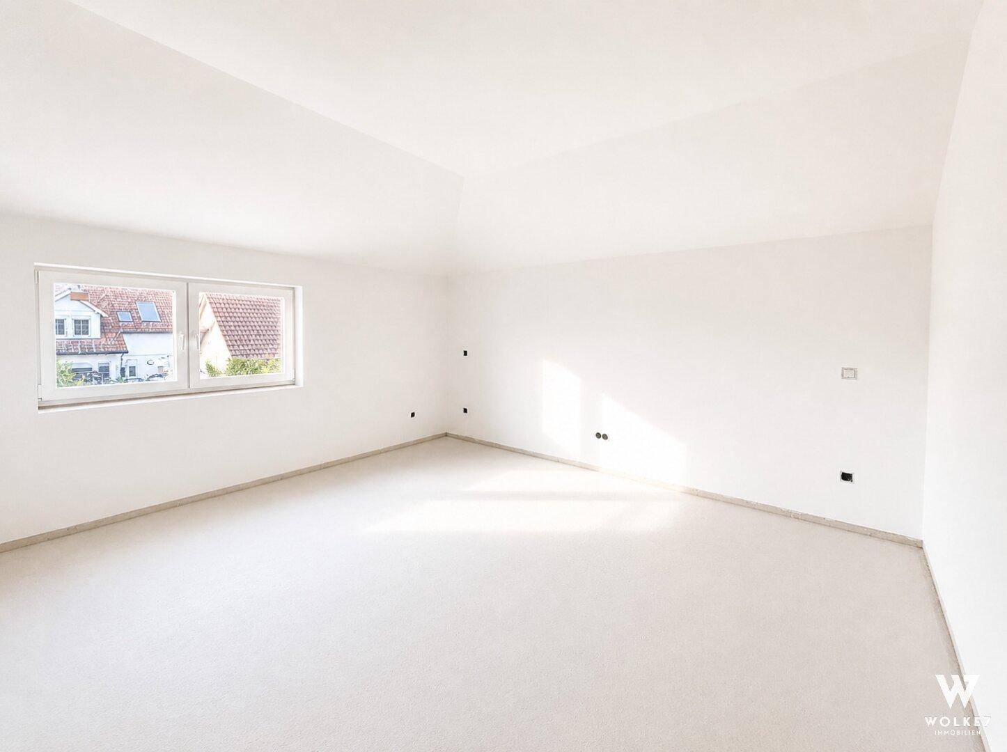 Heller, unmöblierter Raum im Dachgeschoss mit Dachschräge und Fenster.
