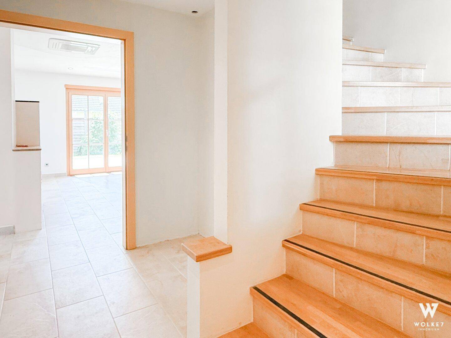 Heller Eingangsbereich mit Treppe und Fliesenboden, der zu den oberen Etagen führt.