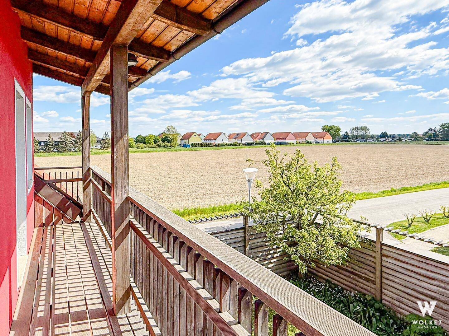 Geräumiger Balkon mit Holzboden und weitem Blick über die Felder.