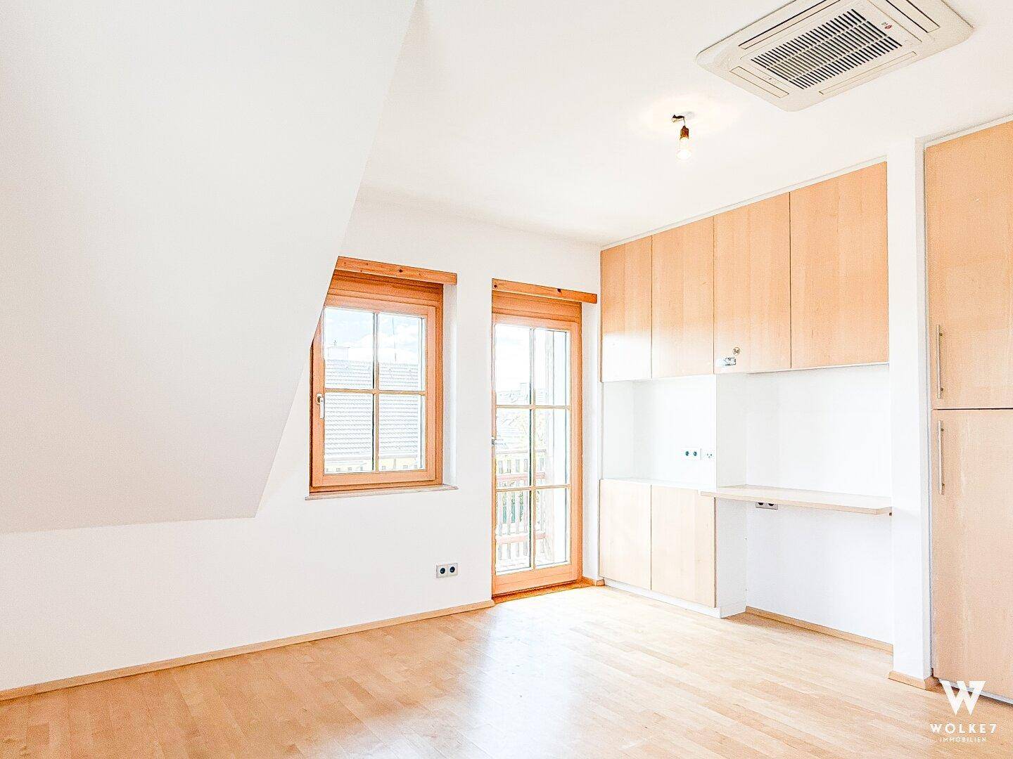 Helles Schlafzimmer mit Dachschräge, Holzboden und Einbauschränken.