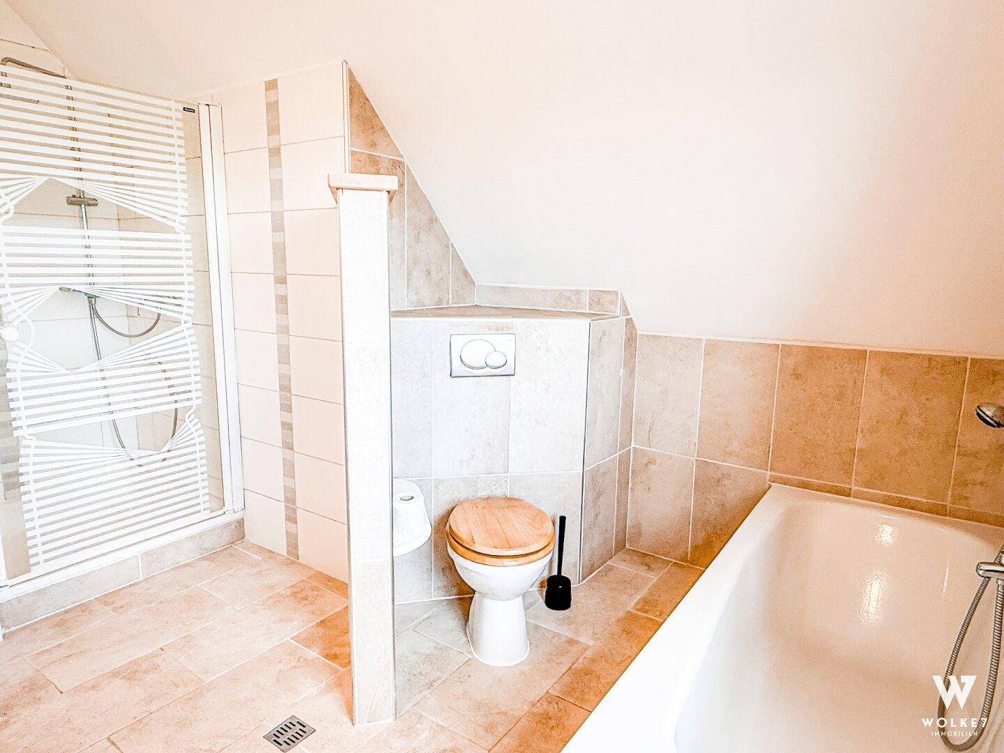 Badezimmer mit Badewanne, Dusche und WC unter einer Dachschräge.