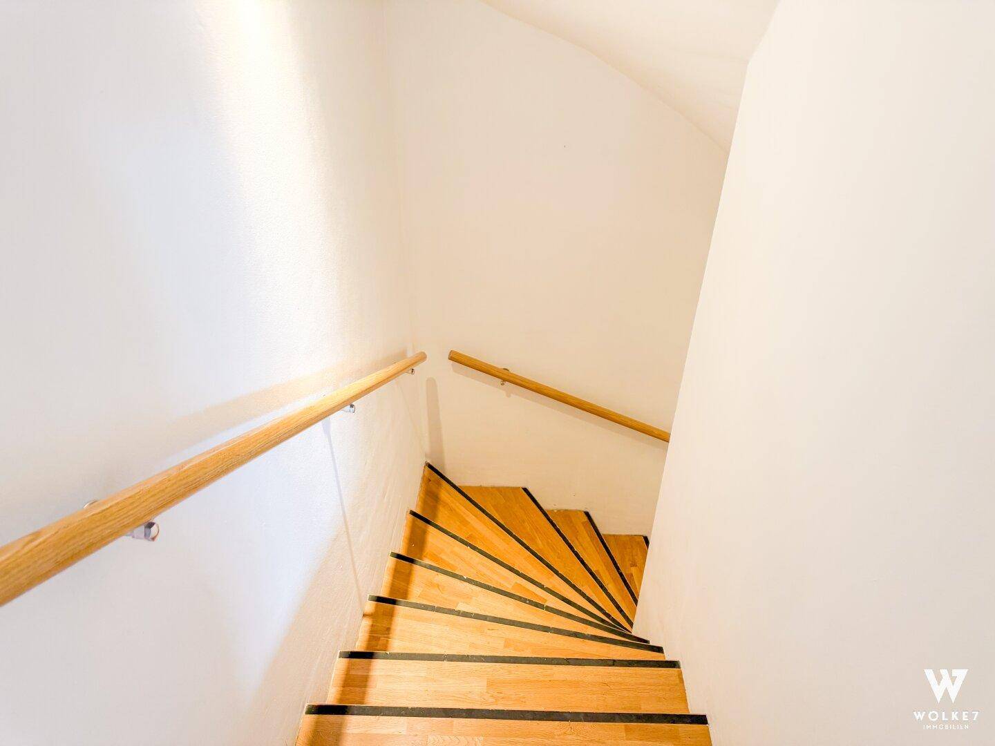 Holztreppe mit Handlauf, die zu den oberen Etagen des Hauses führt.