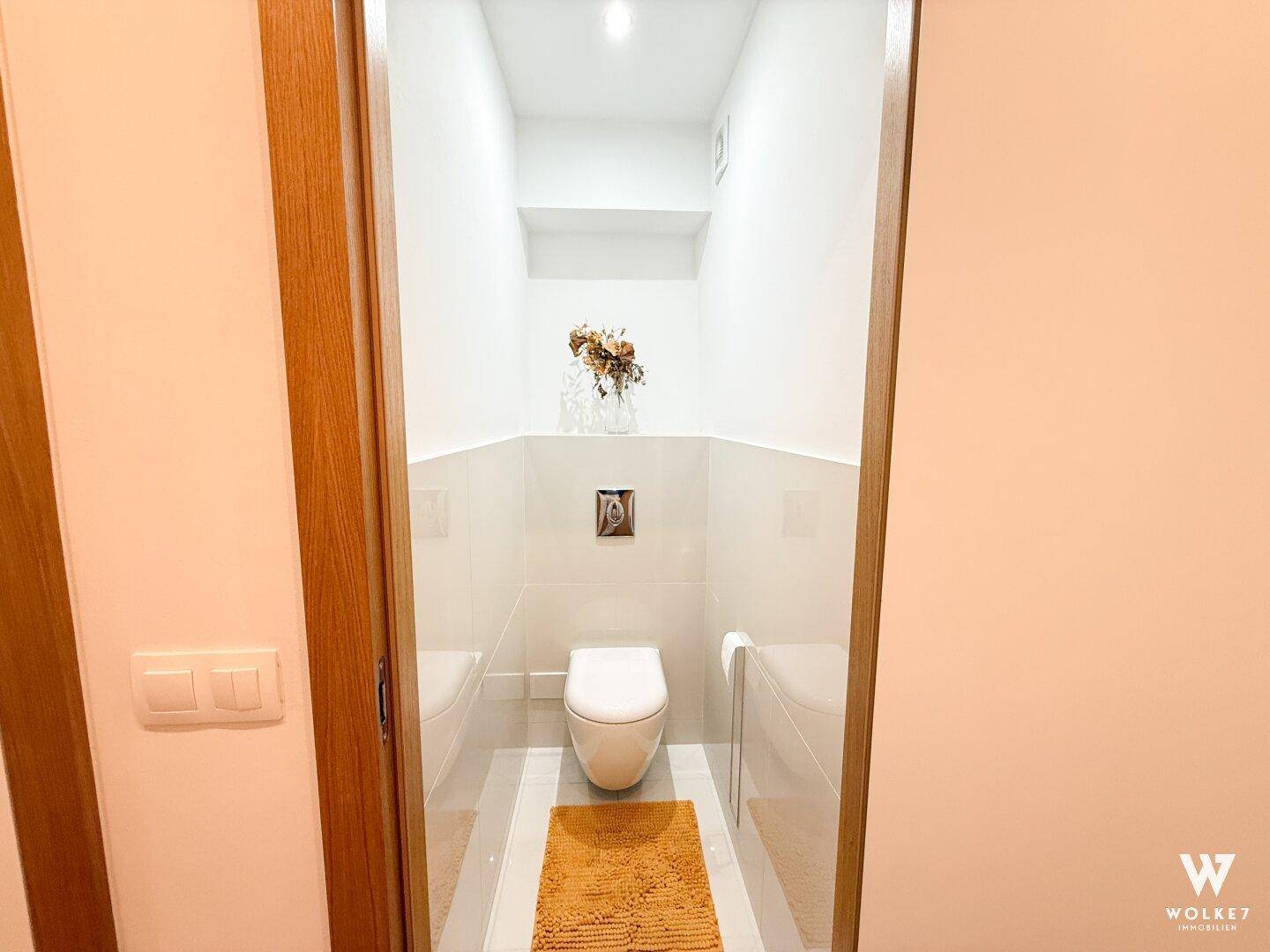 Kompaktes Gäste-WC mit Wand-WC und modernen Fliesen an den Wänden.