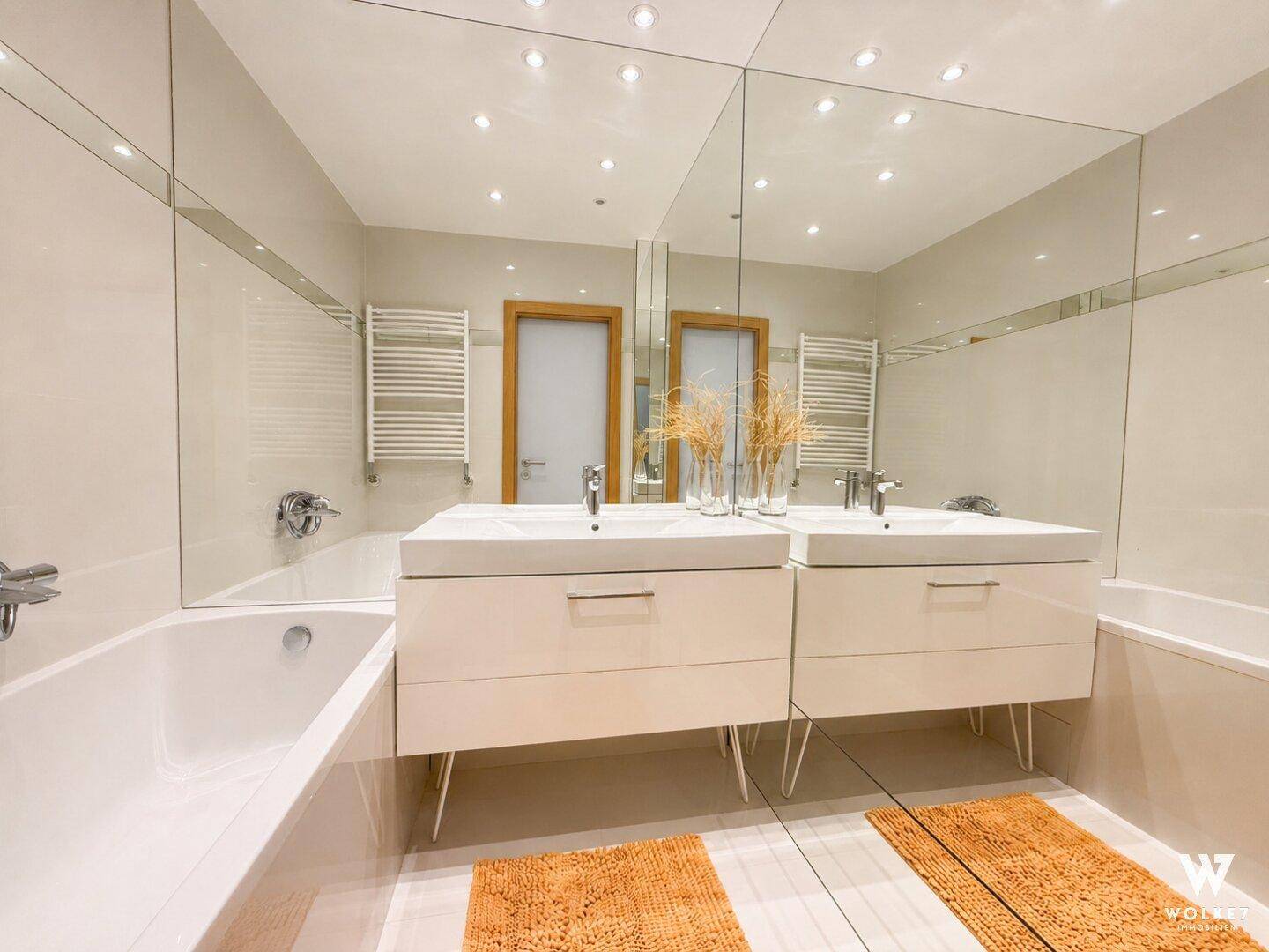 Modernes Badezimmer mit Doppelwaschbecken, Badewanne und Wandspiegeln.
