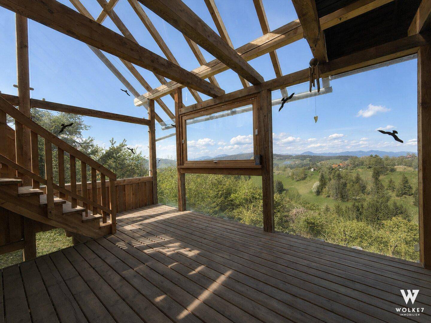 Lichtdurchfluteter Raum mit Holztreppe und Panoramafenstern, die weite Ausblicke bieten.